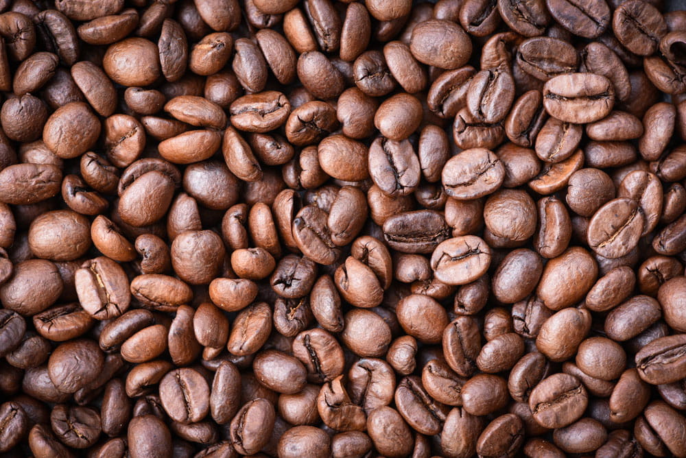 Verschiedene Kaffeebohnen in unterschiedlichen Röstgraden, braune Farbtöne, gleichmäßig verteilt.
