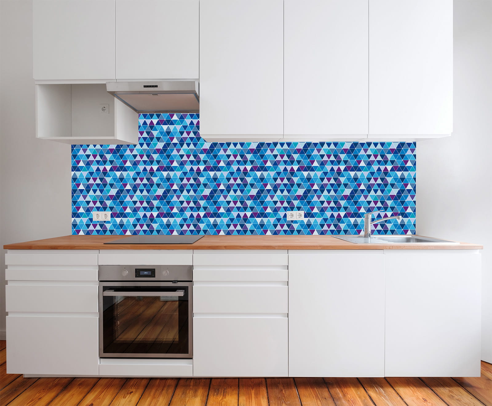 Küche mit weißen Schränken und Holzarbeitsplatte, Rückwand aus blauen Mosaikfliesen mit Dreiecksmuster.
