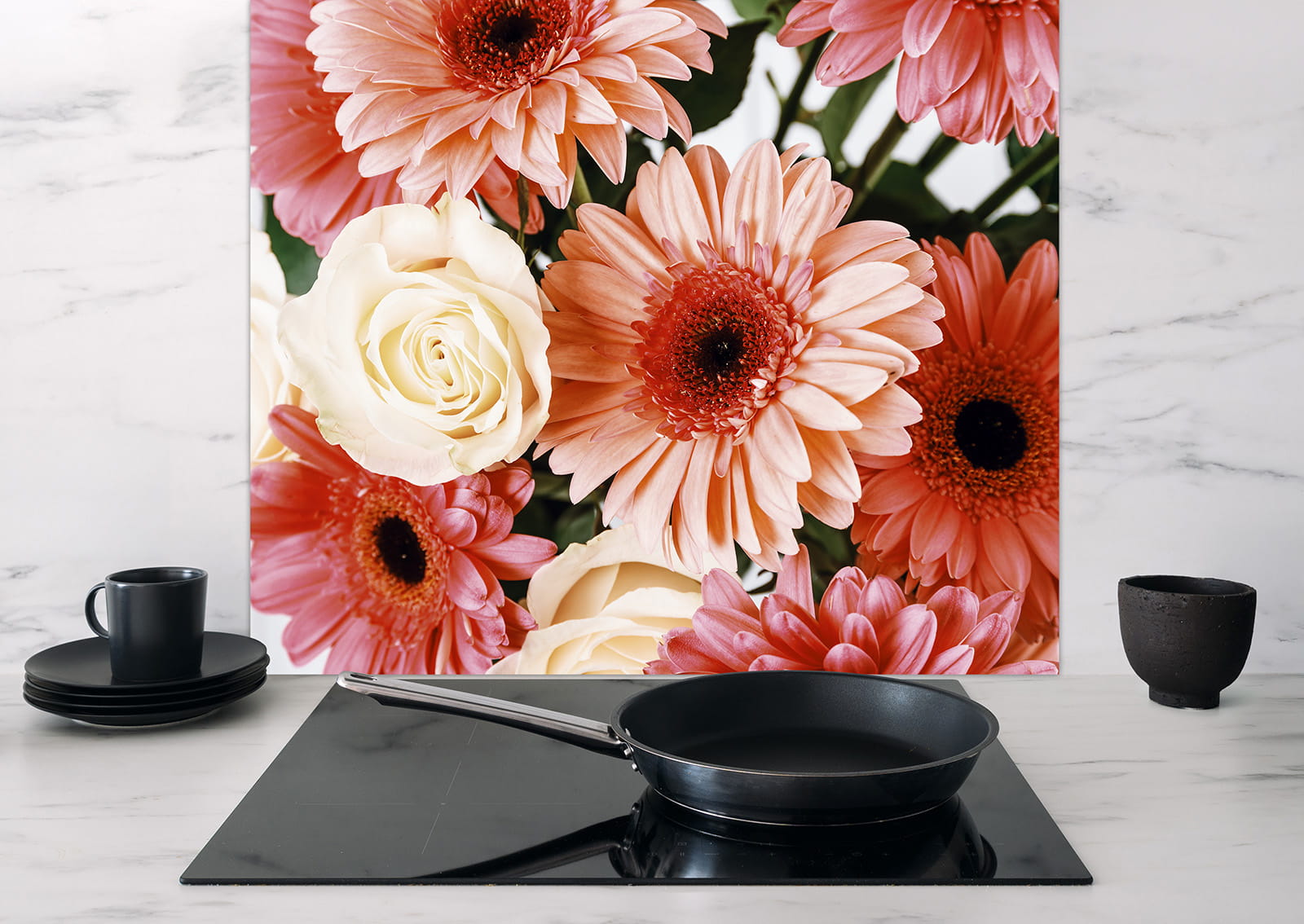 Spritzschutz 'Rosa Blumenstrauß' mit rosa und weißen Blumen, im Hintergrund eine schwarze Kochplatte mit einer Pfanne und Geschirr.
