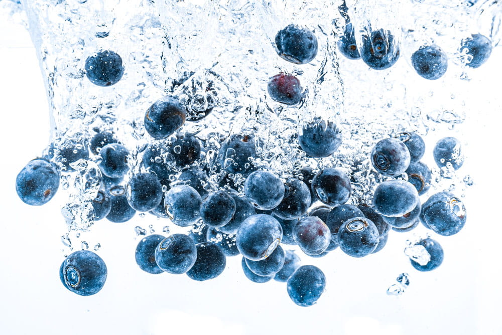 Spritzschutz mit Blaubeeren, die in Wasser eintauchen, sprudelnd und frisch.