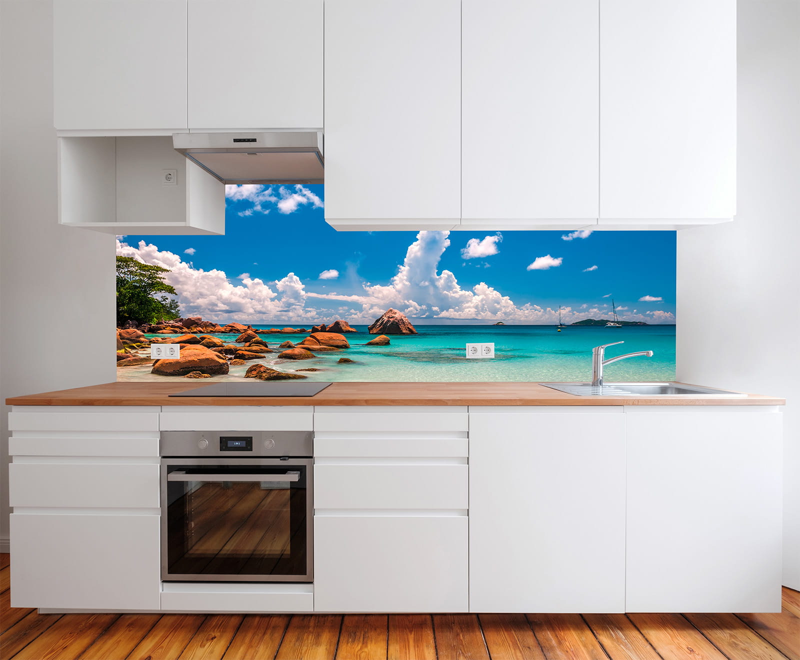 Moderne Küche mit weißem Schrank und Holzarbeitsplatte, im Hintergrund ein Wandbild mit Strand, Meer und Felsen.