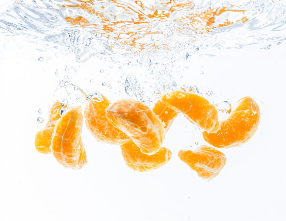 Spritzschutz mit Orangenstücken, die in Wasser eintauchen, für den Einsatz in der Küche.