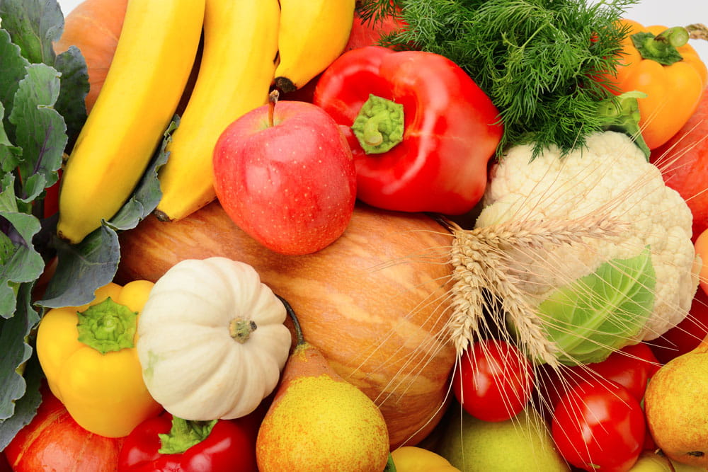 Vielfalt an Obst und Gemüse, darunter Bananen, Äpfel, Paprika, Blumenkohl und Kürbis.