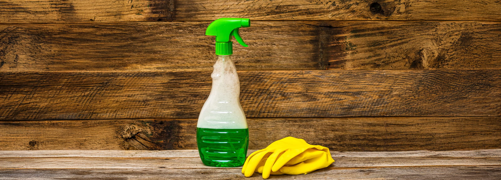 Reinigungsmittel Breit mit Handschuhen Reinigungsmittel Breit in einer Sprühflasche mit grünem Sprühkopf, daneben gelbe Gummihandschuhe.