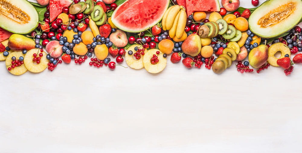 Vielfalt an frischen Früchten, darunter Wassermelonen, Äpfel, Kiwis, Erdbeeren und Trauben, auf einem weißen Hintergrund.