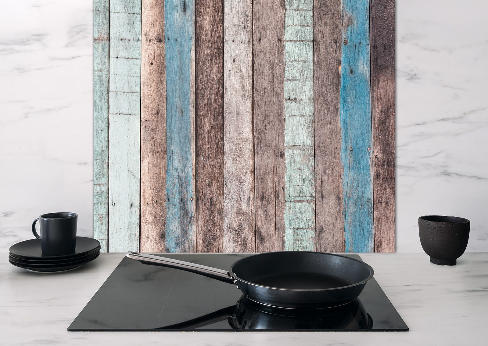 Spritzschutz 'Buntes Holz' von ENTDECKER, zeigt eine Holztextur mit verschiedenen Farben, im Hintergrund eine schwarze Pfanne auf einem Kochfeld.